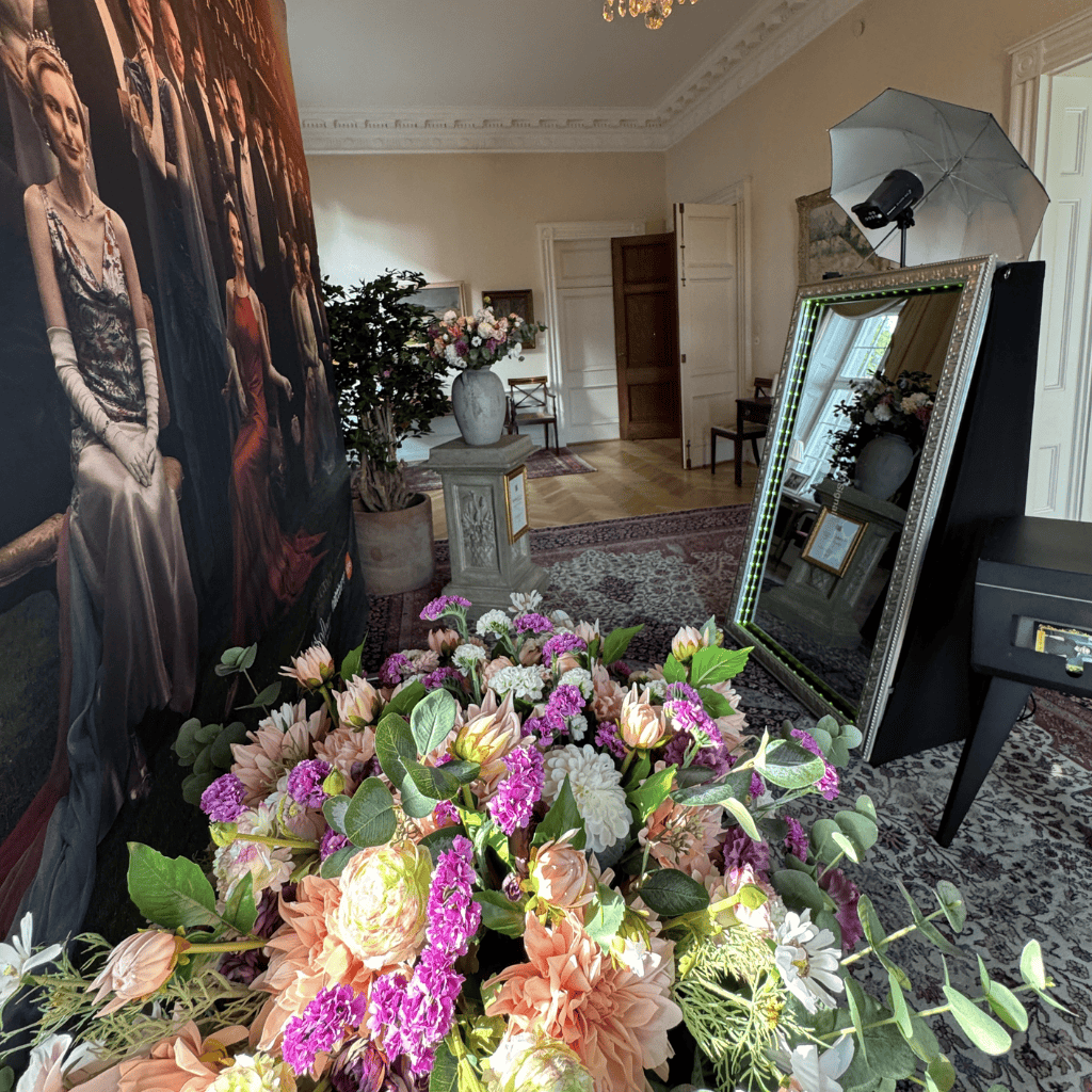 Fotobås i elegant rum med blommor och spegel, perfekt för fest och bröllop i Stockholm.